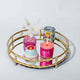 Gold circular bamboo tabletop tray with mirror bottom, featuring pink candle, pink bud vase, Laura Park wine tumbler