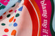 Macro view of white tea towel with multi-colored abstract dots and blush pink tea towel with multi-colored wave design