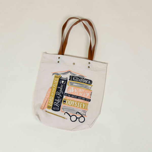 Cream colored tote bag with leather handles featuring illustration of classic books. Perfect gift for a reader.