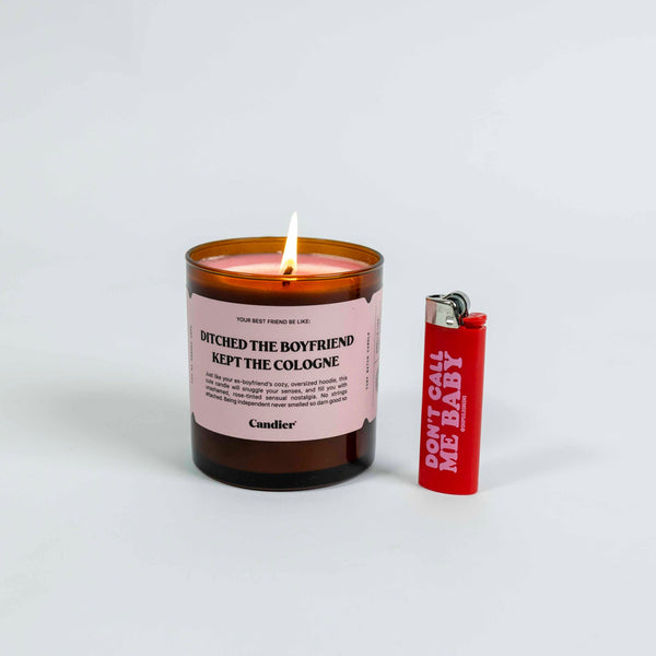 Candier Candle in scent Ditched The Boyfriend, Kept The Cologne, in amber jar with pink label, comes with red lighter with phrase Don't Call Me Baby