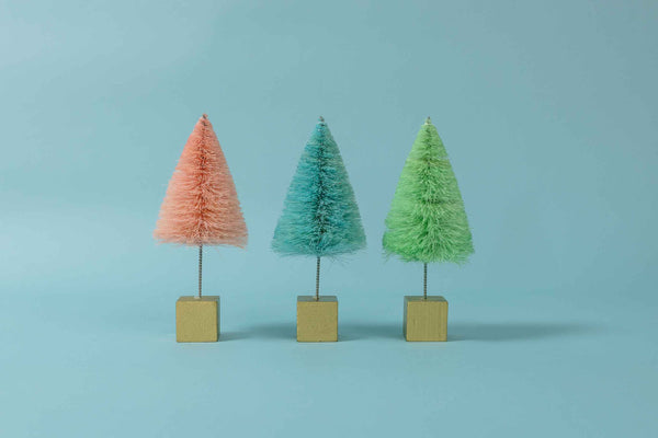 Close up view of set of three squat blue, mint green, and pink sisal decorative trees mounted on metallic gold wood base